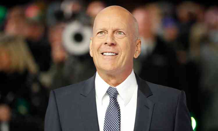 Bruce Willis ao centro com fundo desfocado