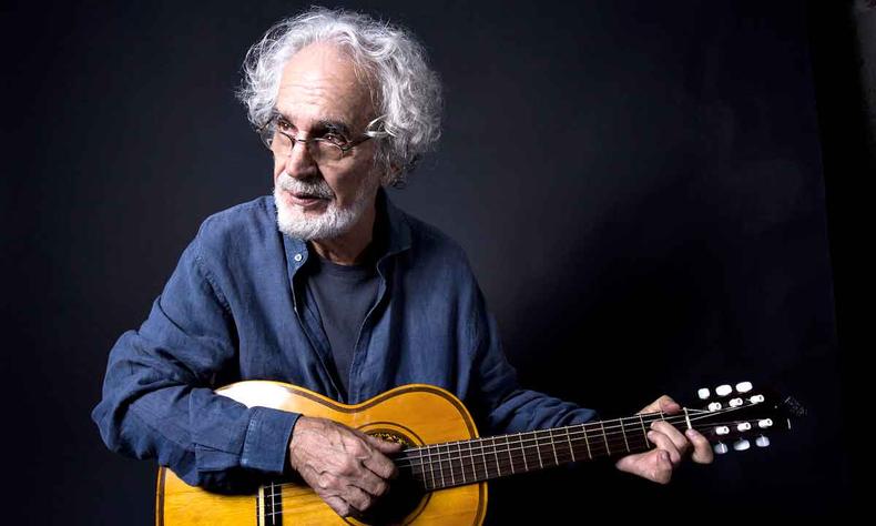 Aos 76 anos, Renato Teixeira se apresenta pela primeira vez sem banda. Repertório de hoje terá inéditas e sucessos (foto: Luiz Tripolli/Divulgação ) Cantor Renato Teixeira, de blusa azul, segura o violão