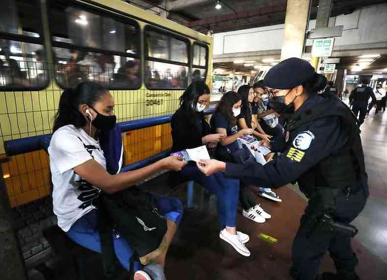Mulheres em uma estao de nibus. Uma agente feminina da Guarda Municipal entrega um folheto a uma mulher usuria das linhas de nibus de Belo Horizonte