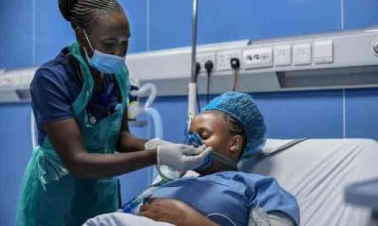 enfermeira assiste paciente com dificuldade de respirar em um leito de hospital