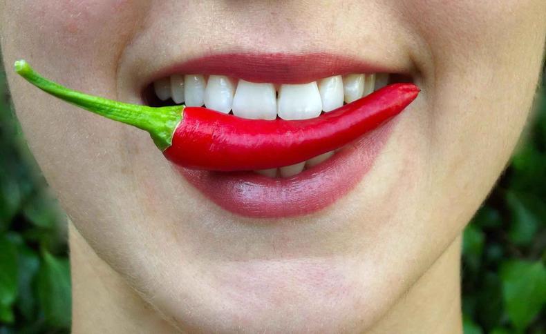 Pepper is a thermogenic food and AMPK regulator (image: englishlikeanative/Pixabay) woman biting pepper, focus on lips
