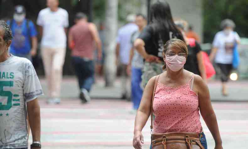 Imagem de mulher usando mscara caminhando na rua