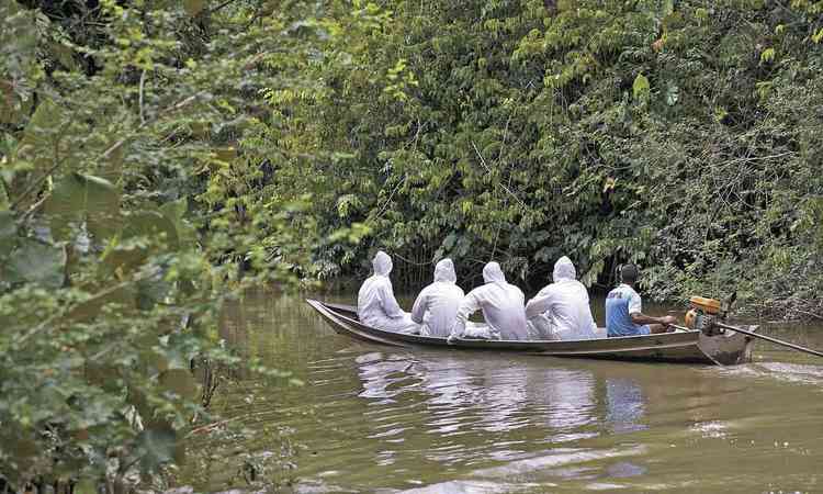 Equipe usando roupa de proteo e mscaras brancas est em canoa em rio da Amaznia