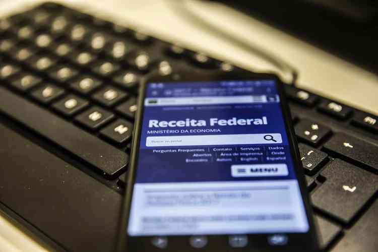 Imagem de um celular em cima de um teclado com o aplicativo da Receita Federal aberto