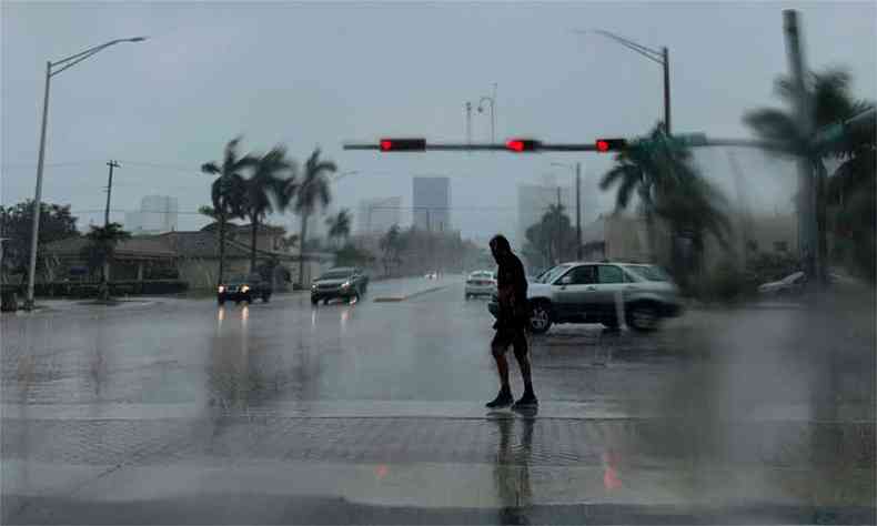 Um homem atravessa a rua durante uma chuva forte em Fort Lauderdale, Flrida, nesta segunda-feira(foto: AFP / Eva Marie UZCATEGUI )