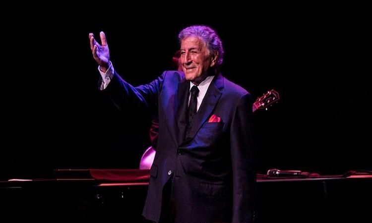 o cantor americano tony bennett de terno, com uma luz roxa em volta dele 