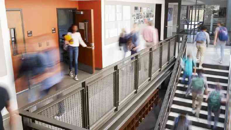 Vultos de alunos circulando entre portas, escadas e corredores de uma escola