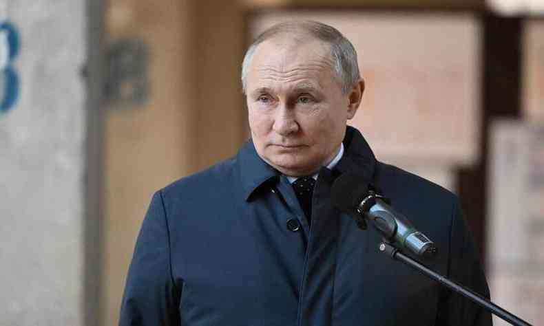Putin em primeiro plano com um microfone a sua frente