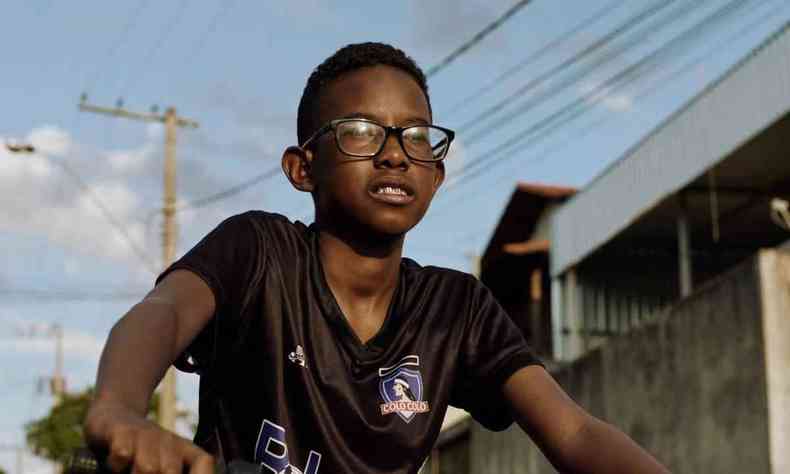 Na foto, protagonista de 'Marte UM', um adolescente negro de culos, anda de bicicleta 