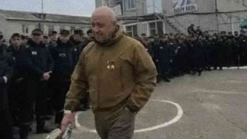 Yevgeny Prigozhin caminhando em frente a prisioneiros em p lado a lado