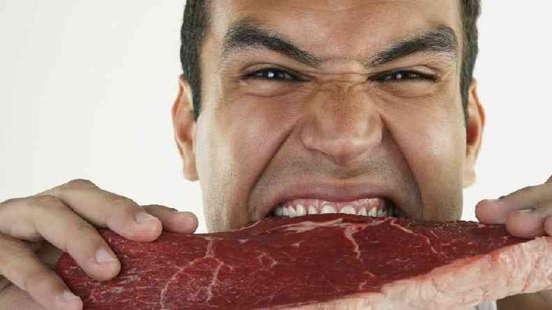 Homem mordendo carne crua