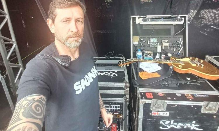 Sandro Ramos olha para a cmera tendo ao fundo equipamentos no palco de um show

