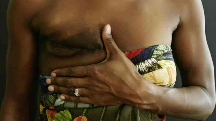 Mulher negra segura o seio com cicatriz de mastectomia