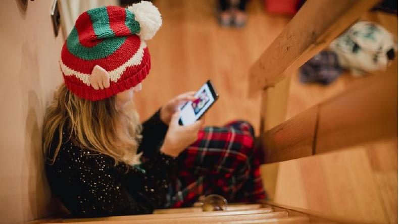 Jovem de gorro de Natal vendo rede social