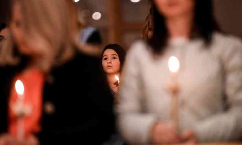 Uma menina segura uma vela enquanto participa da missa de Pscoa realizada na catedral Madre Teresa em Pristina em 16 de abril de 2022