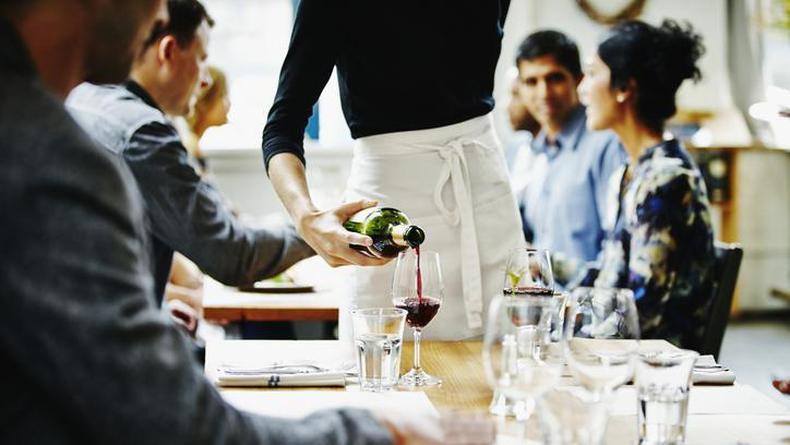Garom servindo vinho em restaurante