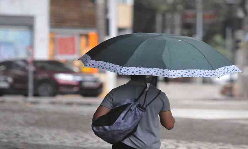Chuva no centro da cidade, homem com guarda chuva aberto