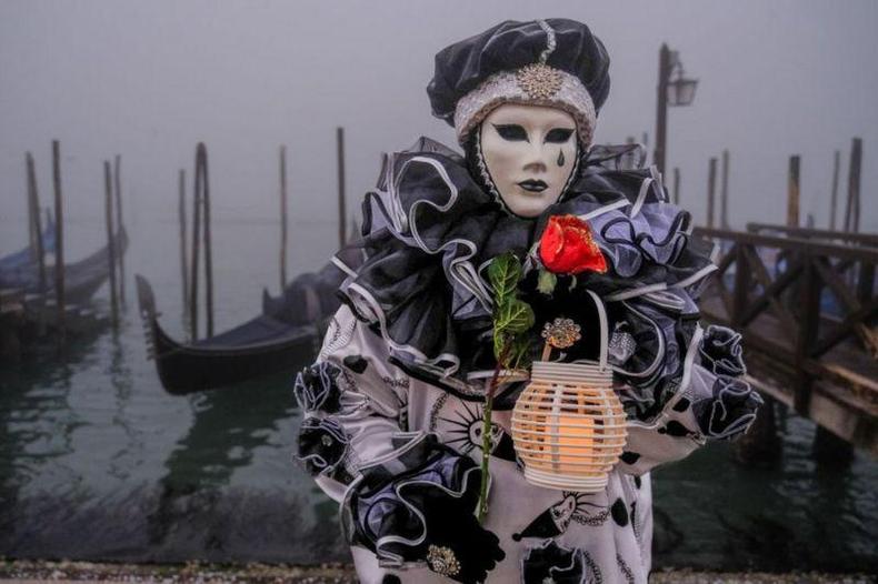 Apesar dos canais secos, o famoso carnaval de Veneza foi realizado na semana passada(foto: Getty Images) Pessoa fantasiada com máscara no carnaval de Veneza em frente ao canal