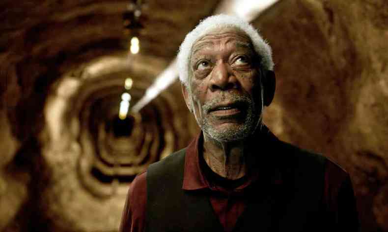 O ator Morgan Freeman, de camisa preta, em tnel, olha para cima 