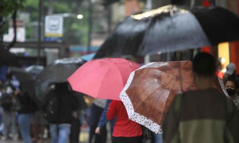 Pessoas com sombrinha durante chuva 