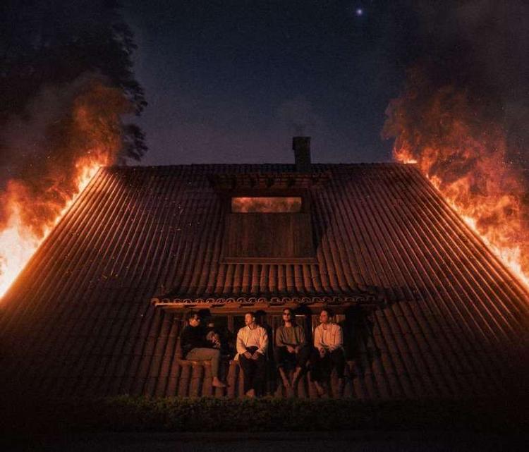 Pedro, Zani, Chico e Jorge sentados em frente a uma casa pegando fogo
