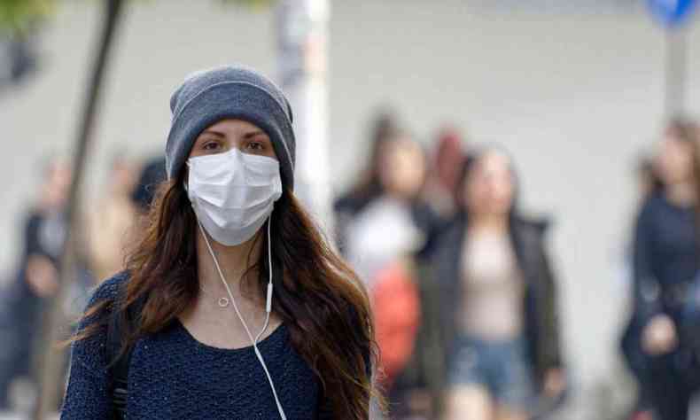 Uma mulher usa mscara facial contra a covid e fones de ouvido