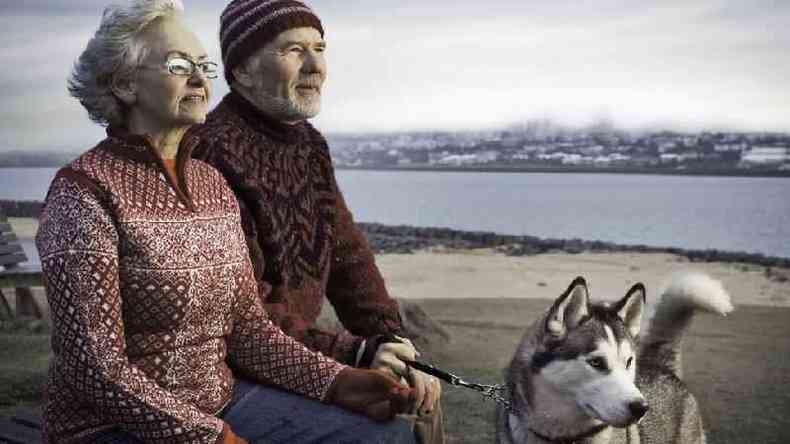 Casal de islandeses com cachorro posa em frente a um lago