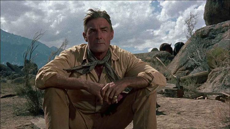 O ator Randolph Scott usa trajes de cowboy e chapu em cena do filme O resgate do bandoleiro
