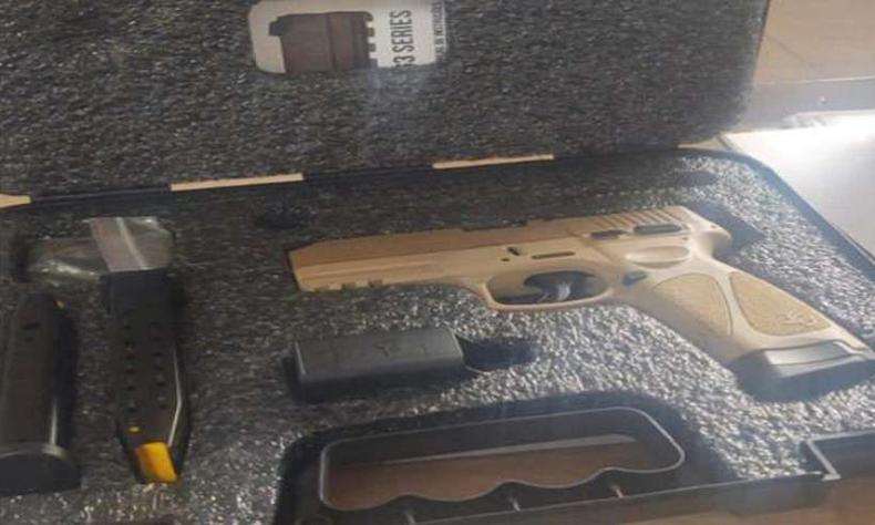 uma arma, de cor bege, dentro de uma caixa