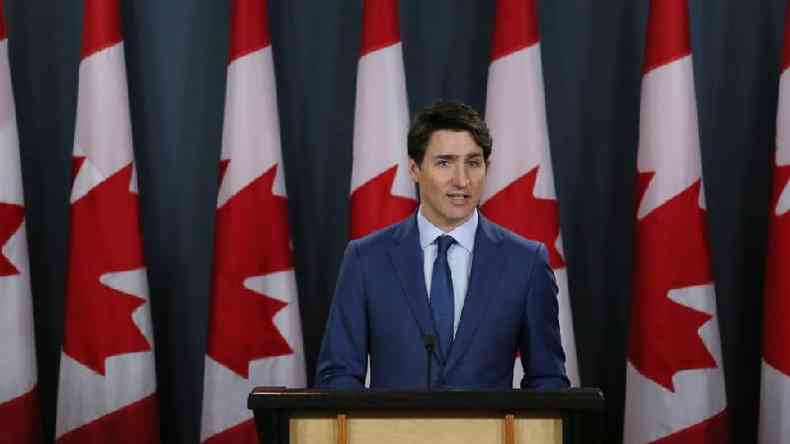 Justin Trudeau diante de bandeiras do Canad