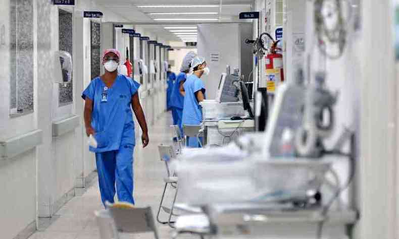 foto ilustrativa de um corredor de hospital com leitos vazios e funcionarios da Sade com roupas azuis
