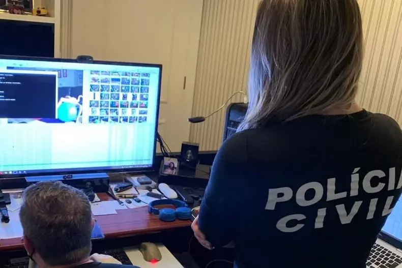 Policiais civis olham computador