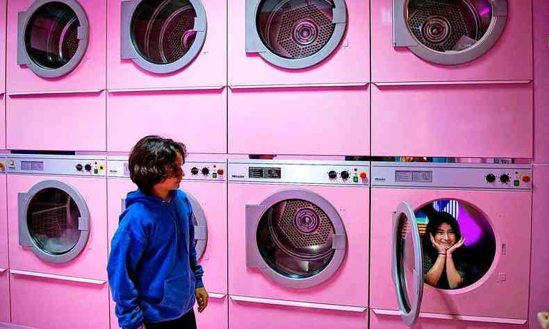 garoto observa mulher que posa para fotos dentro de mquina de lavar cenogrfica cor de rosa 