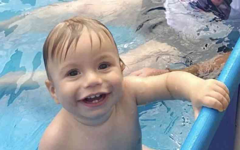 menino rindo para foto dentro de uma piscina 
