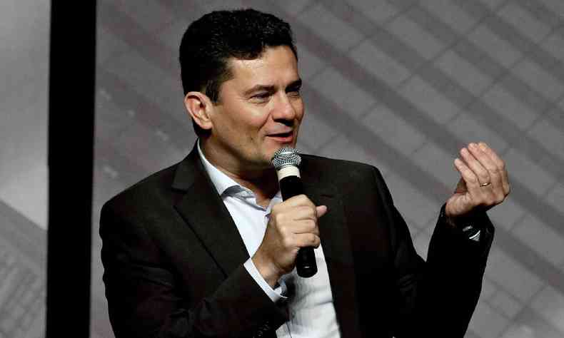 Sergio Moro de terno preto e camisa branca, sem gravata, falando ao microfone enquanto gesticula com a mo esquerda