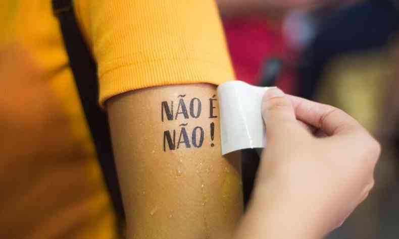 Pessoa usando uma tatuagem removvel escrito 'No  no!' no brao