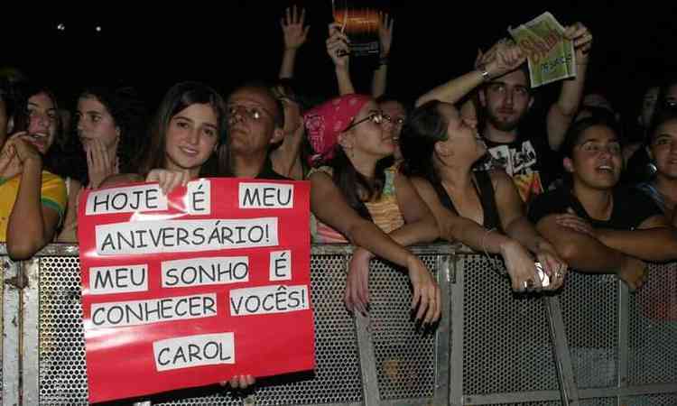 F, na frente do palco,  mostra cartaz pedindo para conhecer msicos do Skank