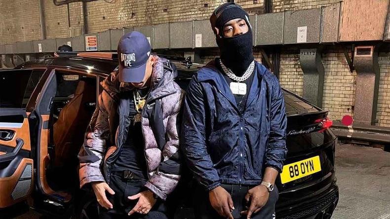 L7nnon e o rapper britnico Tion Wayne encostados num carro em cena de videoclipe