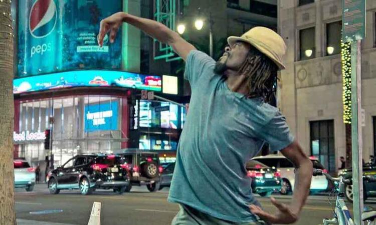 De camiseta e chapu, bailarino Ronnie 'Astaire do futuro' Willis faz pose de bal com braos abertos em esquina do Hollywood Boulevard
