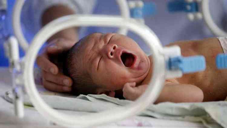 Um beb recm-nascido bocejando em uma incubadora