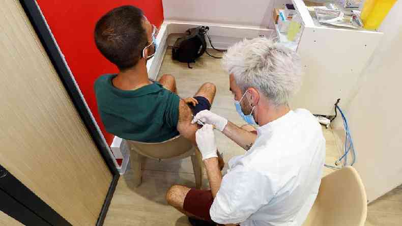 Profissional de sade vacinando homem contra o monkeypox