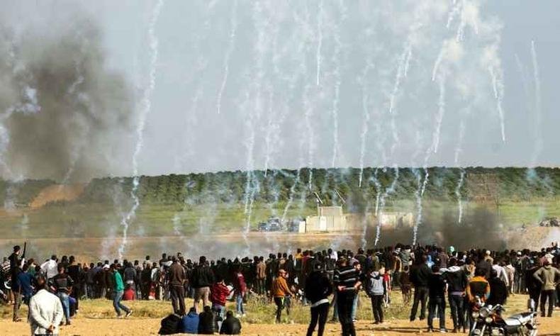 Manifestantes palestinos tentam se proteger do g�s lacrimog�neo disparado pelas for�as de seguran�a israelense durante confrontos em comemora��o ao Dia da Terra, perto da fronteira com Israel, a leste da cidade de Gaza(foto: MAHMUD HAMS/AFP)