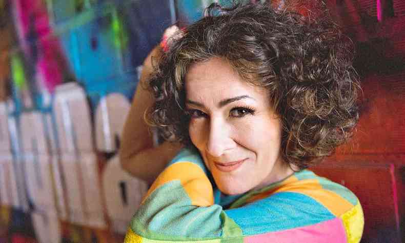 Maquiada e com camisa multicolorida, Patricia Ahmaral encara a cmera 