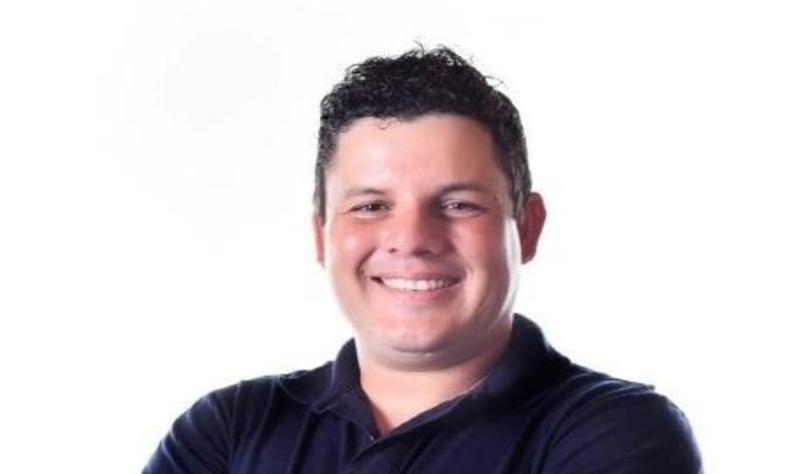 Lucas sorri em foto de campanha; ele  um homem branco e novo