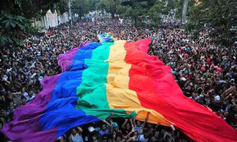 Bandeira LGBTQIAP+ gigante sobre um mar de pessoas