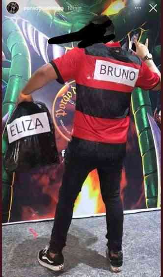 homem com a camisa do Flamengo, com o nome de Bruno e um saco de lixo escrito Eliza
