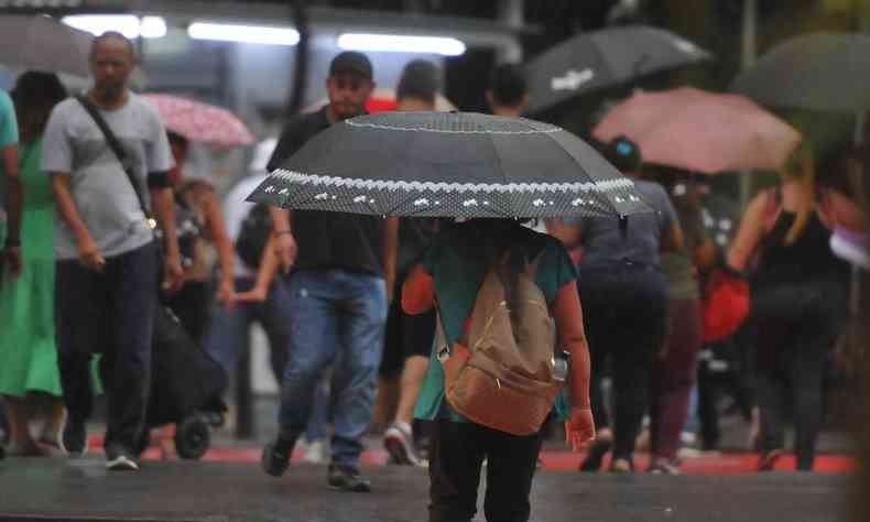 Imagem de uma pessoa andando de guarda-chuva pelas ruas de BH