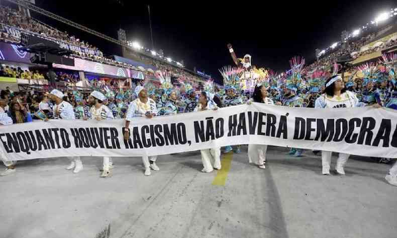 Membros da Beija-Flor entrando na avenida segurando uma faixa com os dizeres: Enquanto houver racismo, no haver democracia