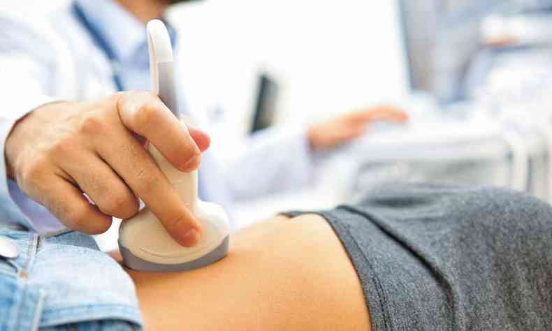 Foto mostra mdico manipulando aparelho de ultrassom sobre o ventre de paciente