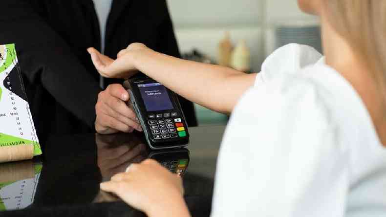 Uma mulher pagando sua refeio em um caf usando um chip de pagamento sem contato implantado em sua mo